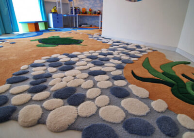 "Detail of textured children's rug – loop and cut pile combination imitating pebbles and sand" width="100%" />