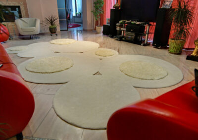 "Multi-level cream rug with round shapes on tiled floor and red couches"