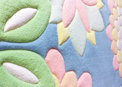 Фрагмент овального ковра в холодных оттенках с рельефной стрижкой ворса